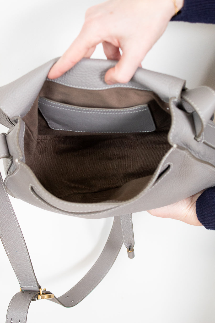 Inside view of grey leather saddle crossbody bag on white background