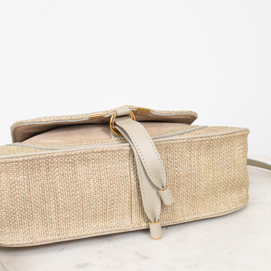 Beige woven handbag with a strap on a white background