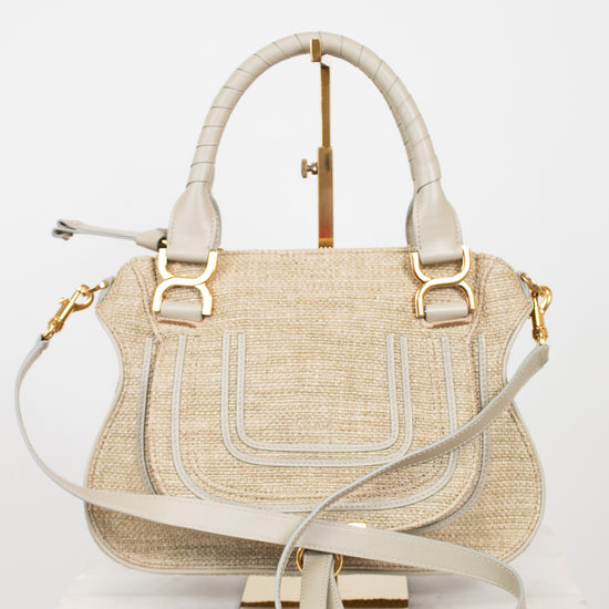 Beige handbag with straw texture and gold accents on a white background