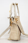 Beige handbag with straw texture and gold accents on a white background
