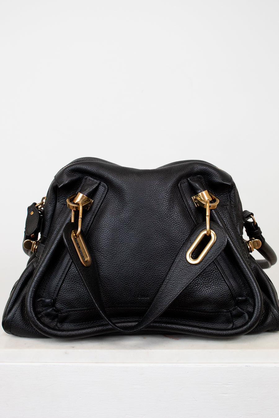 Black handbag with gold hardware on a white background