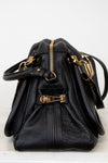 Black leather handbag with gold hardware on a white background