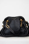 Black leather handbag with gold hardware on a white background