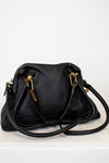 Black handbag with gold hardware on a white background