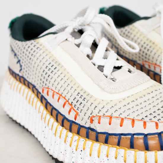 White sneaker with colorful sole on a light gray background