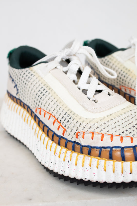 White sneaker with colorful sole on a light gray background