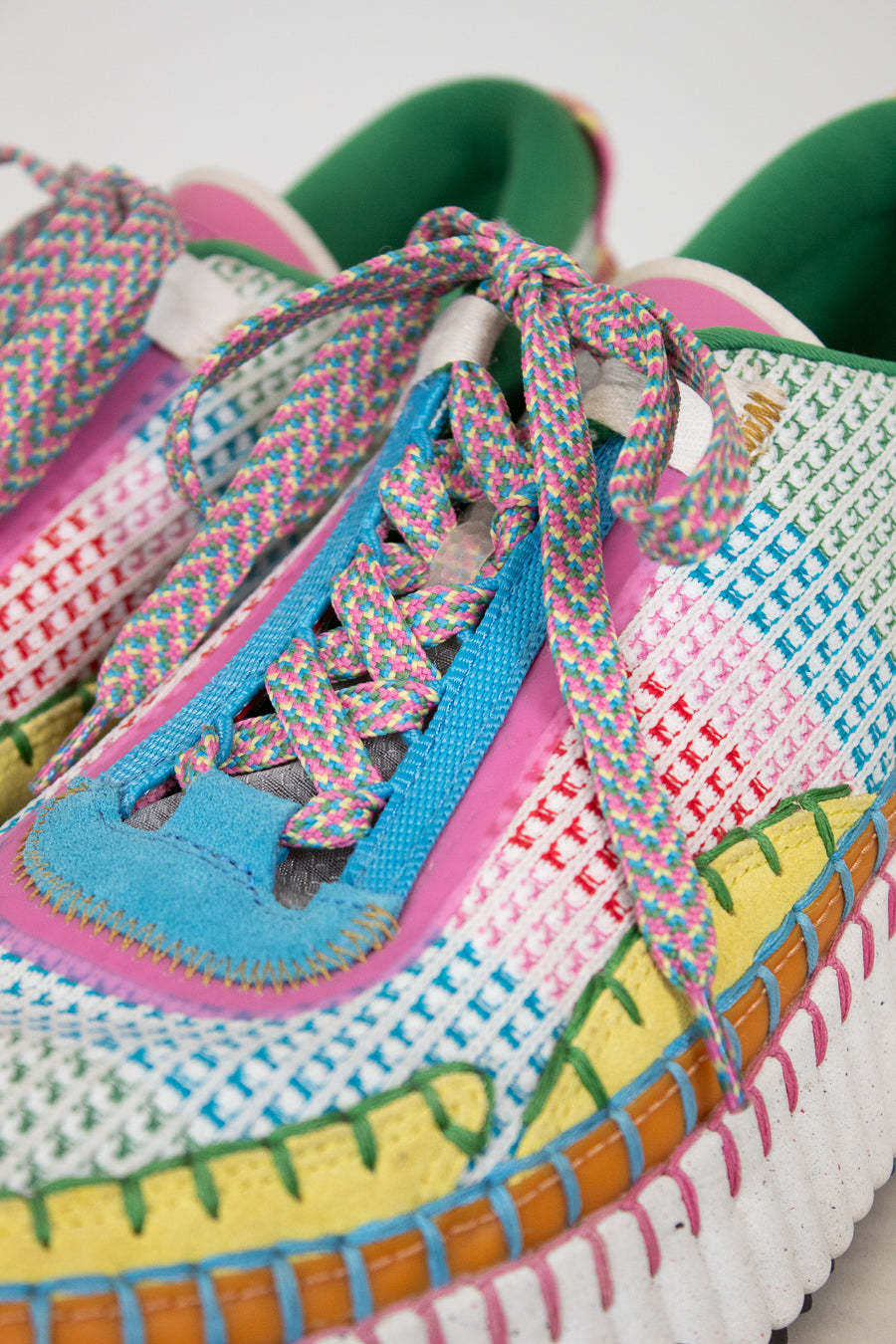 Colorful woven sneakers with patterned laces on a white background