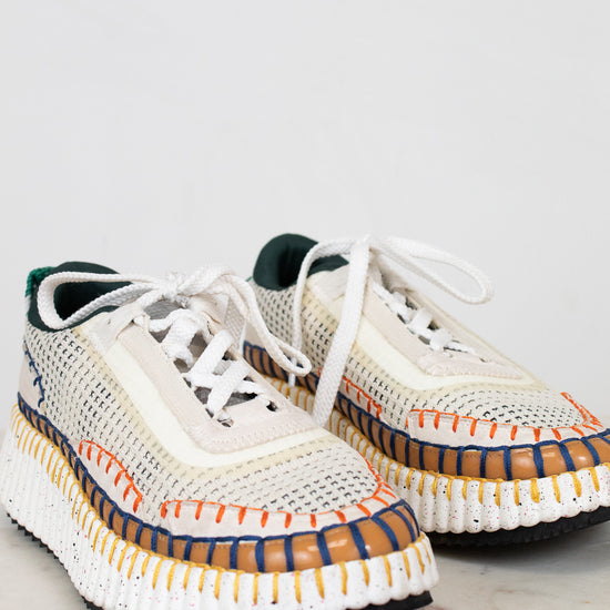 Pair of white sneakers with colorful accents on a light gray background