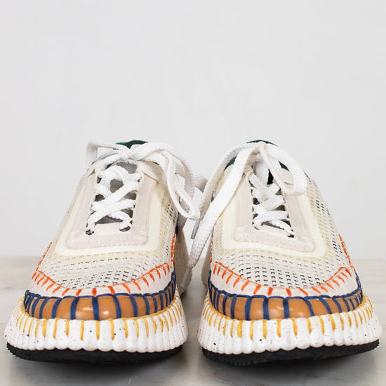 Pair of white sneakers with colorful soles on a light gray background