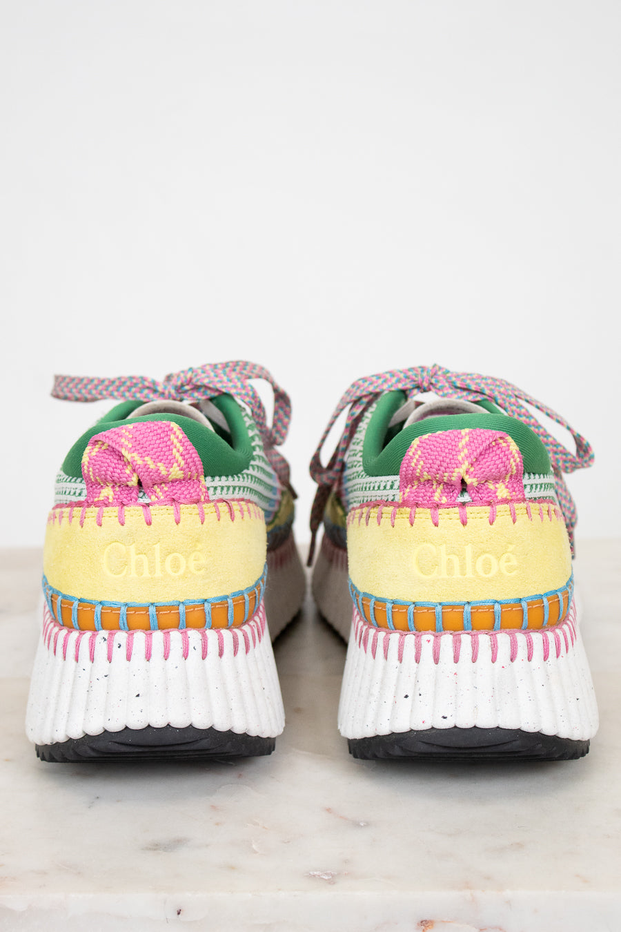 Colorful sneakers with a Chloe brand logo on back sitting on a light background