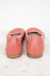 A pair of dusty pink leather ballet flats with scalloped edges, shown from the back on a white marble surface against a white background.