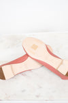 A pair of pink leather ballet flats shown from the bottom, displaying the light beige insole and heel counter, resting on a white marble surface.