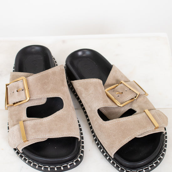 Beige sandals with gold buckles on a white background