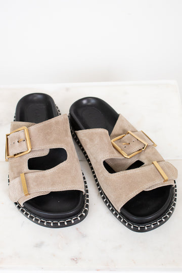 Beige sandals with gold buckles on a white background