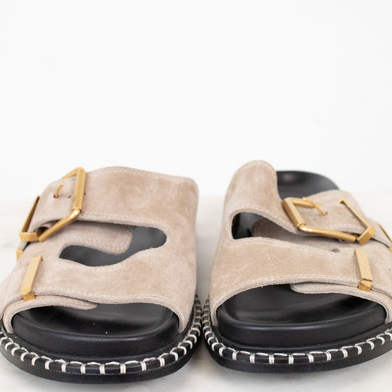 Pair of beige sandals with gold buckles on a white background