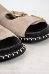 Pair of beige sandals with black soles on a light background