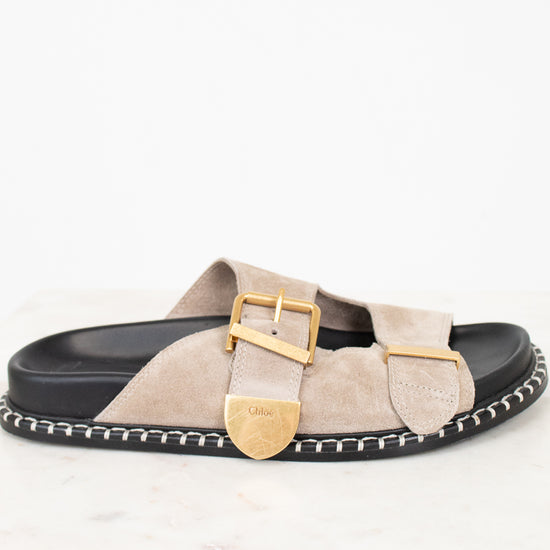 Beige sandal with gold buckle on a white background