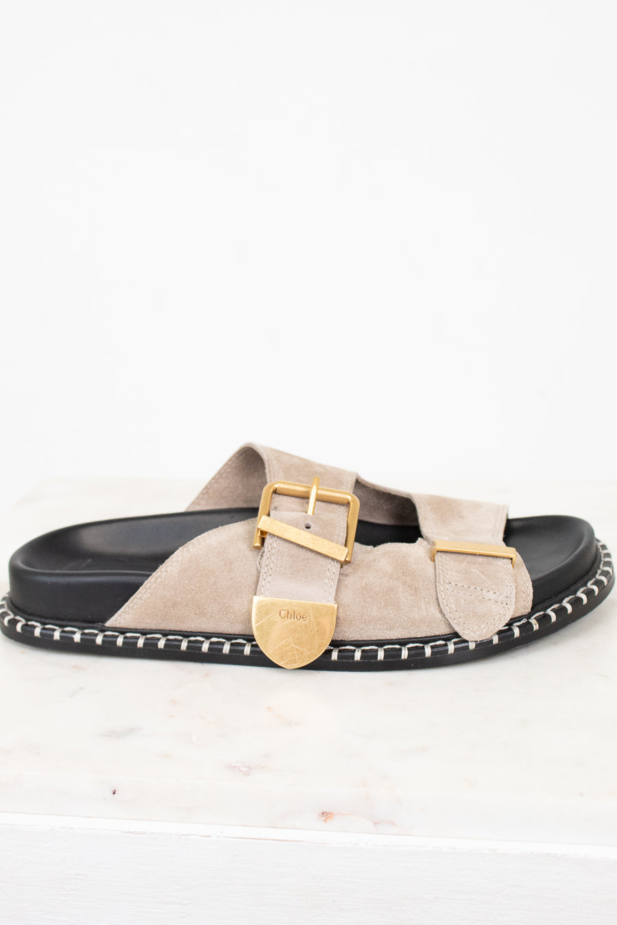 Beige sandal with gold buckle on a white background