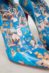 Blue high-heeled shoes with colorful patterned design on a light background