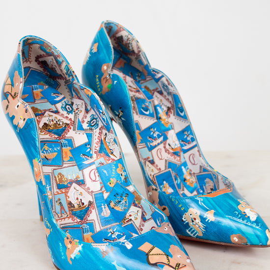 Pair of blue high-heeled shoes with decorative pattern on a white background