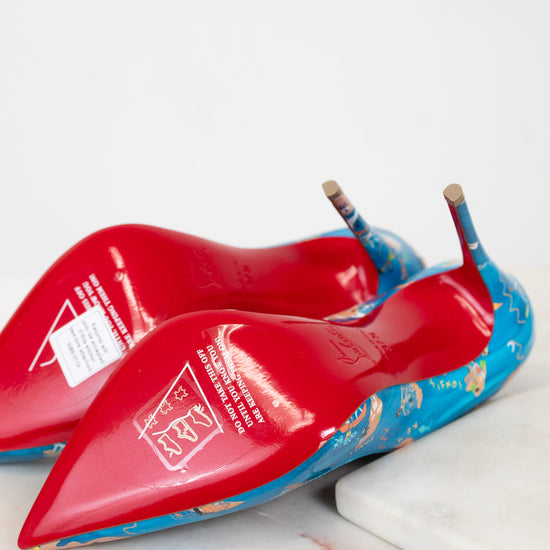 Red high-heeled shoes with blue soles on a white surface