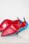 Red high-heeled shoes with blue soles on a white surface