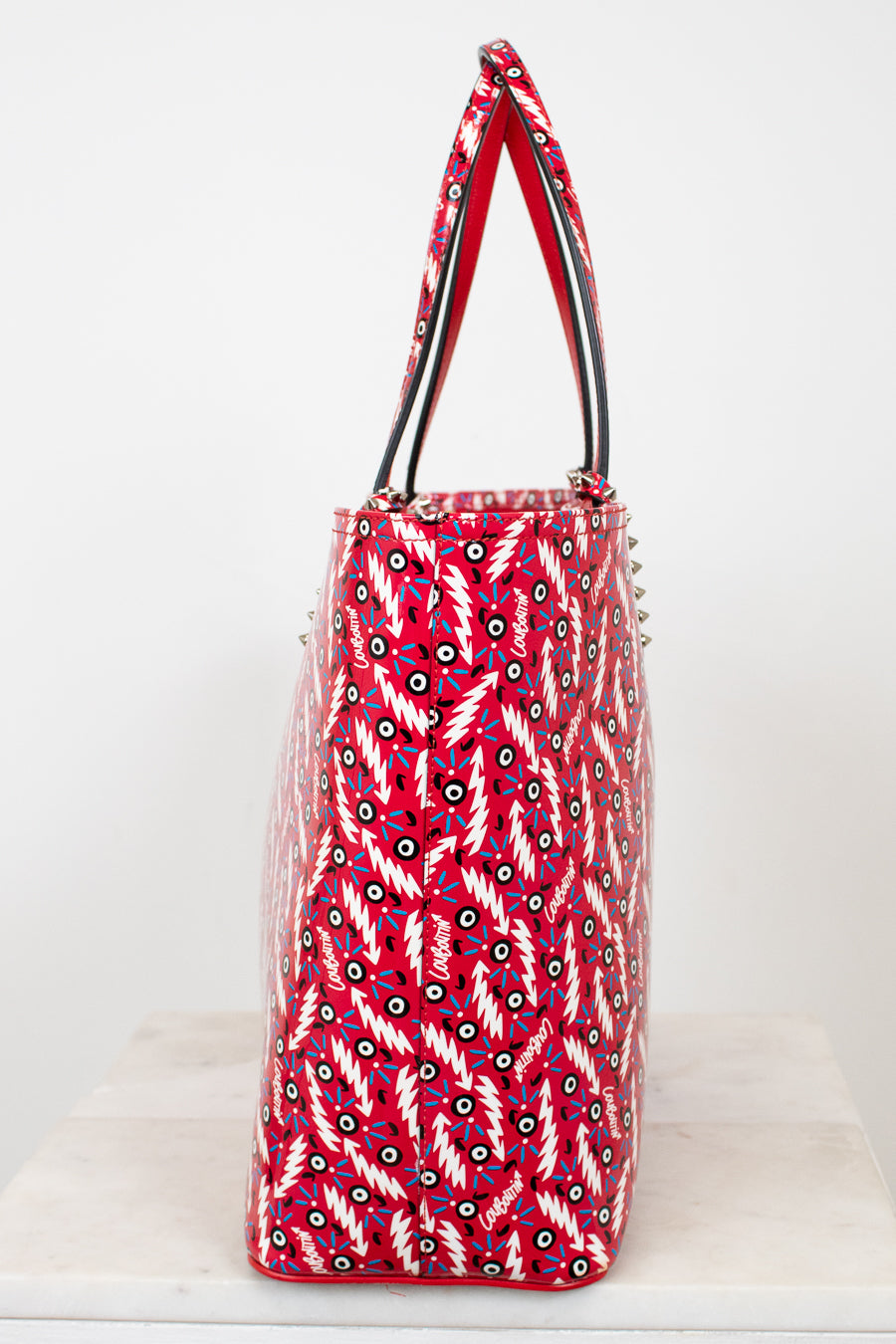 Red patterned handbag with silver studs on a white background