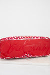 Red base of Louboutin tote with abstract pattern on a white background