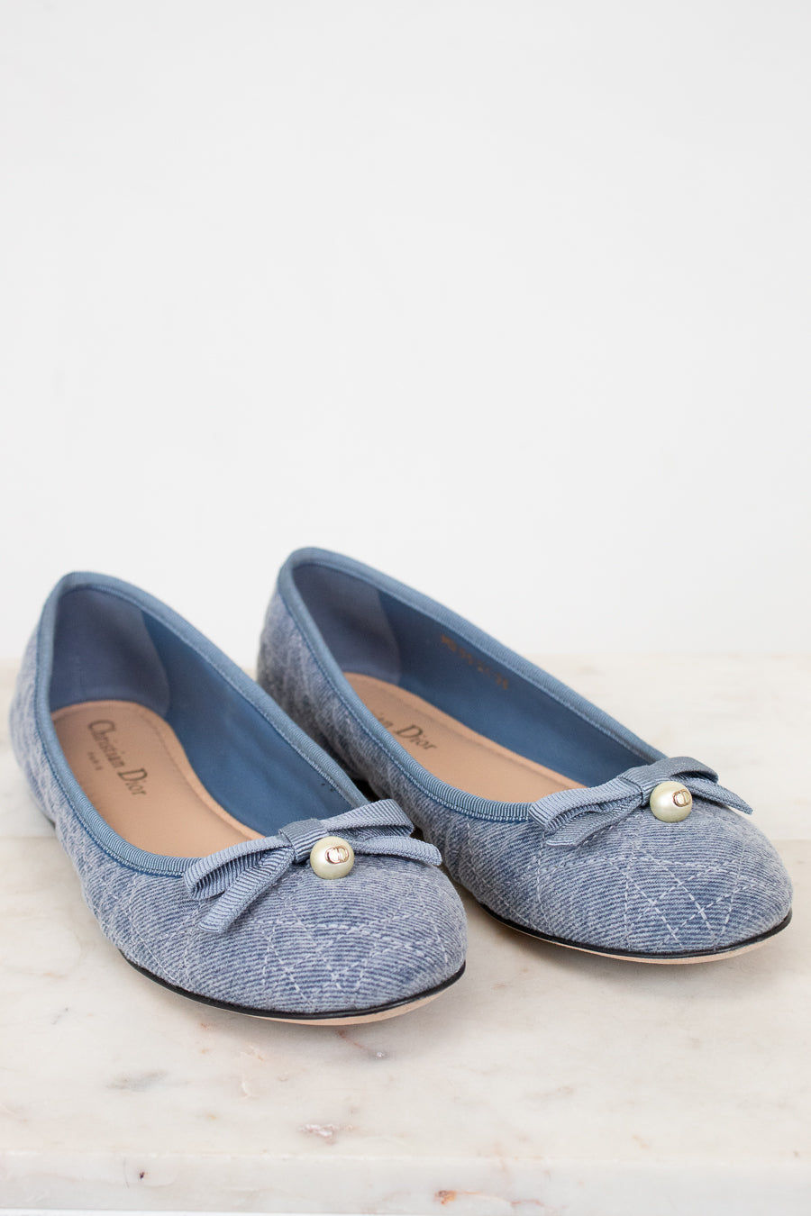 Pair of blue shoes with bow details on a white background