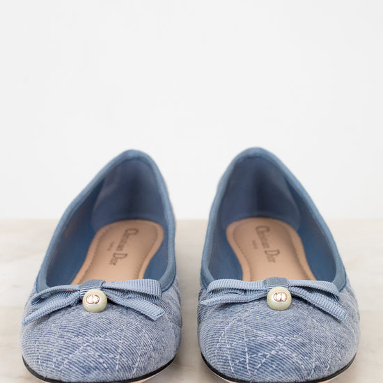 Pair of blue denim shoes with pearl embellishments on a light background