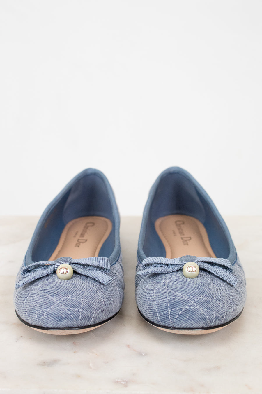 Pair of blue denim shoes with pearl embellishments on a light background