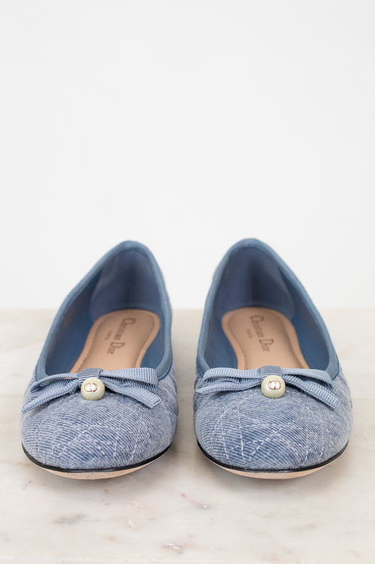 Pair of blue denim shoes with pearl embellishments on a light background