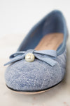 Blue flat shoe with a bow and pearl detail on a light background