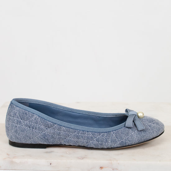 Blue flat shoe with a bow on a light gray background