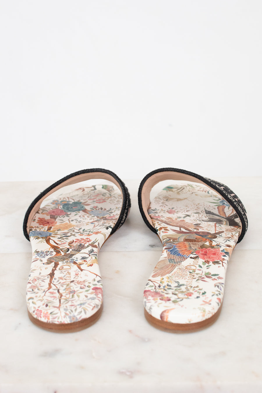 Another view of floral sandals on a marble surface and white background