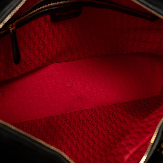 Close-up of the interior of a black handbag showing a bright red lined compartment with a gold-tone zipper and a repeating monogram pattern on the lining.