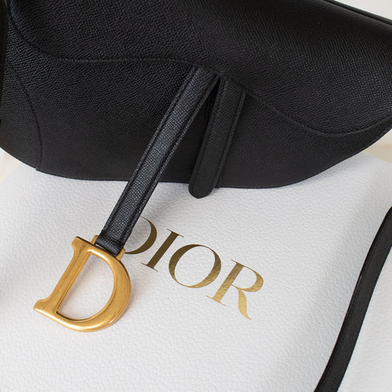 Close-up of black 'Christian Dior' saddle bag on white 'DIOR' box