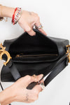 Black handbag being held open by hands