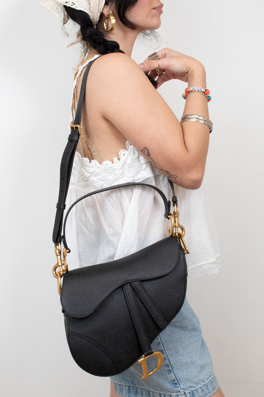 Black saddle bag being held by person