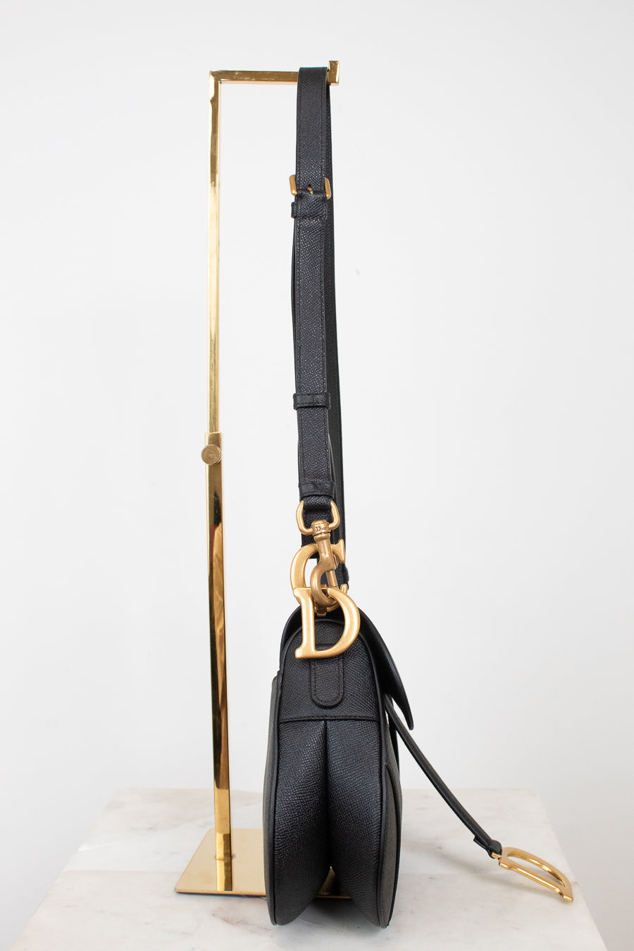 Side view of black bag on gold stand with visible logo