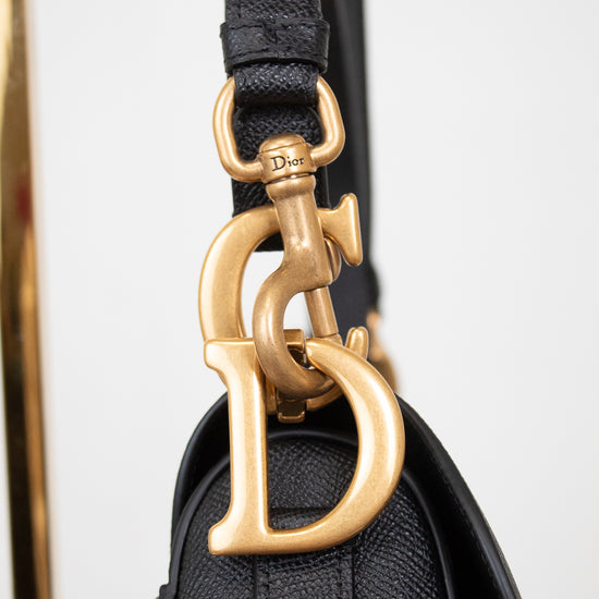 Close-up of gold 'D' logo with visible 'Dior' branding on hardware