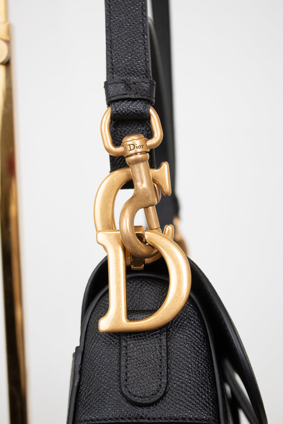 Close-up of gold 'D' logo with visible 'Dior' branding on hardware