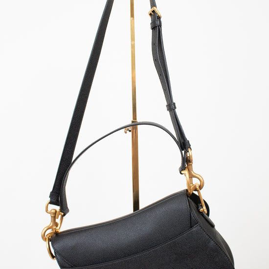 Back view of black bag with black straps on gold stand