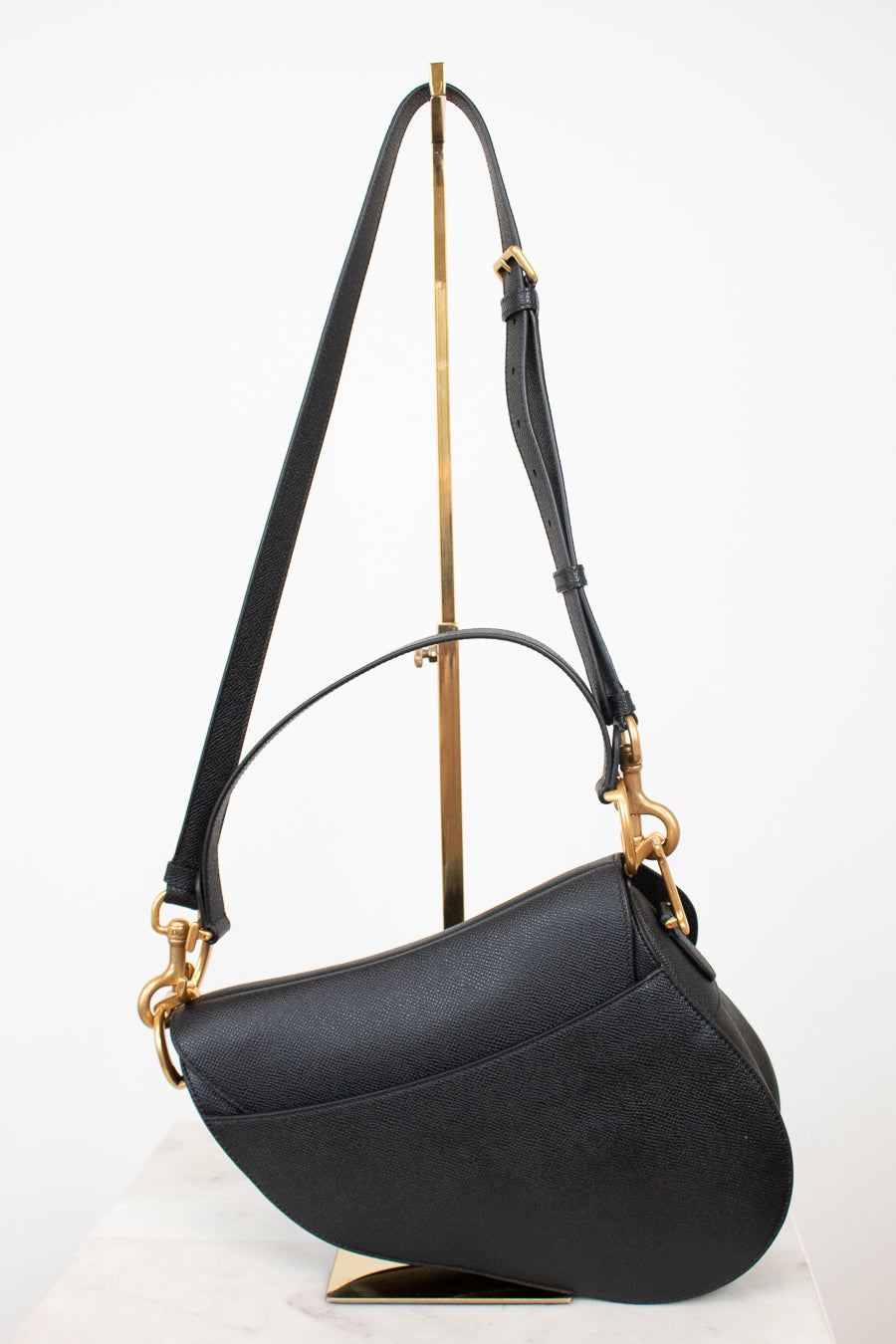 Back view of black bag with black straps on gold stand