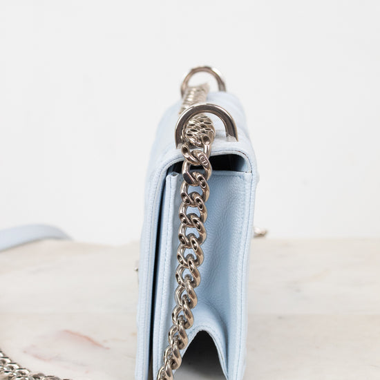 A light blue leather shoulder bag shown from the side, featuring a silver-tone chain strap and a silver-tone metal ring detail, set against a plain white background.
