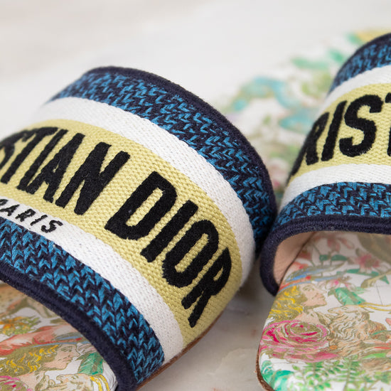 Close up of floral sandals with 'Christian Dior' strap on a marble surface