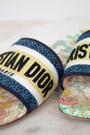 Close up of floral sandals with 'Christian Dior' strap on a marble surface