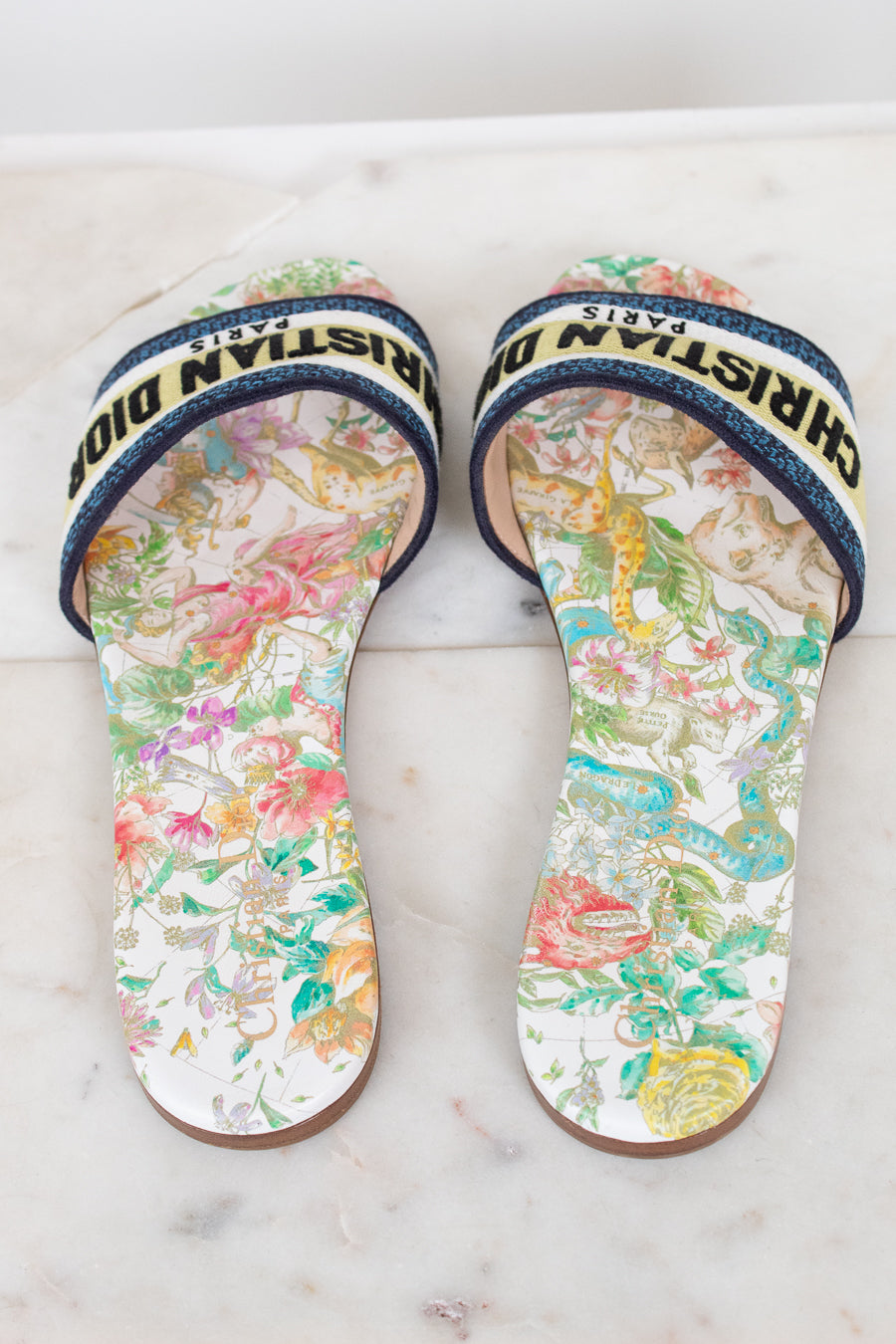 Floral sandals with 'Christian Dior' blue/black/white/chartreuse strap on a marble surface