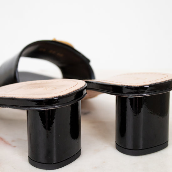 Black high-heeled shoes with beige soles on a light background