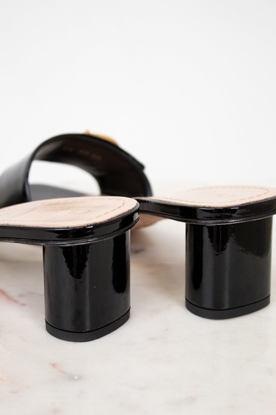 Black high-heeled shoes with beige soles on a light background